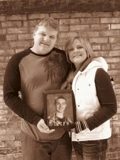 A man and woman holding a picture of a soldier.